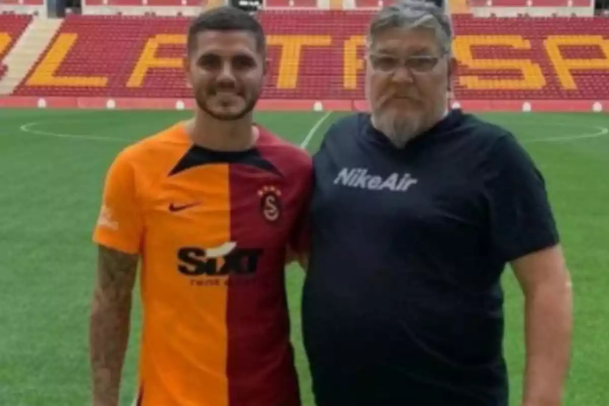 Two people pose on the field of a soccer stadium, one wearing a Galatasaray uniform and the other wearing a black Nike Air t-jersey. Two people pose on the field of a soccer stadium, one wearing a Galatasaray uniform and the other wearing a black Nike Air t-jersey.