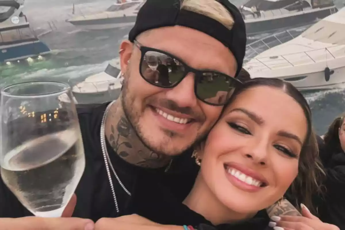 Couple smiling and hugging while enjoying a glass of white wine with yachts in the background on the sea Couple smiling and hugging while enjoying a glass of white wine with yachts in the background on the sea