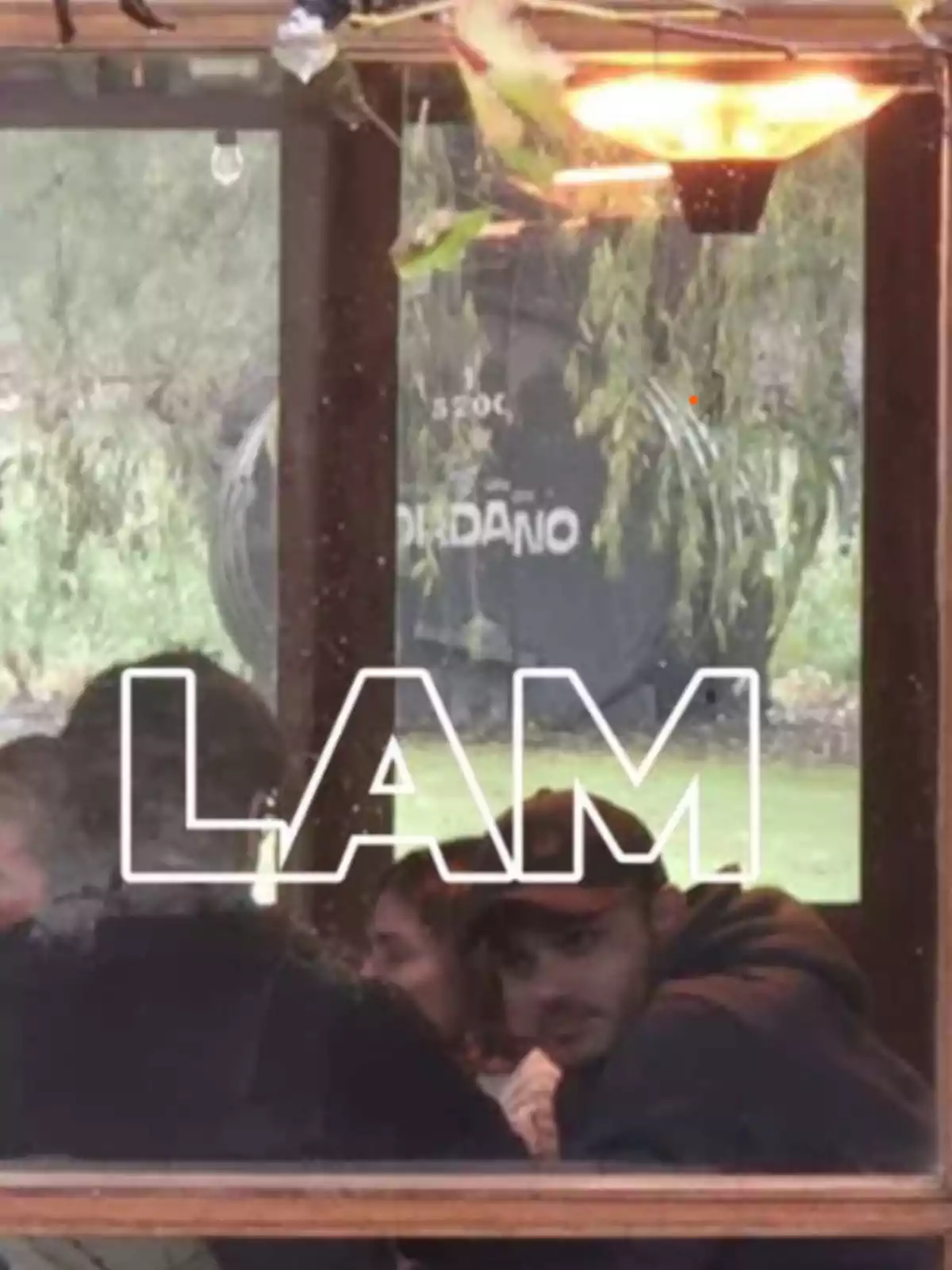 People sitting inside a venue seen through a window with the word LAM in large letters on the glass People sitting inside a venue seen through a window with the word LAM in large letters on the glass