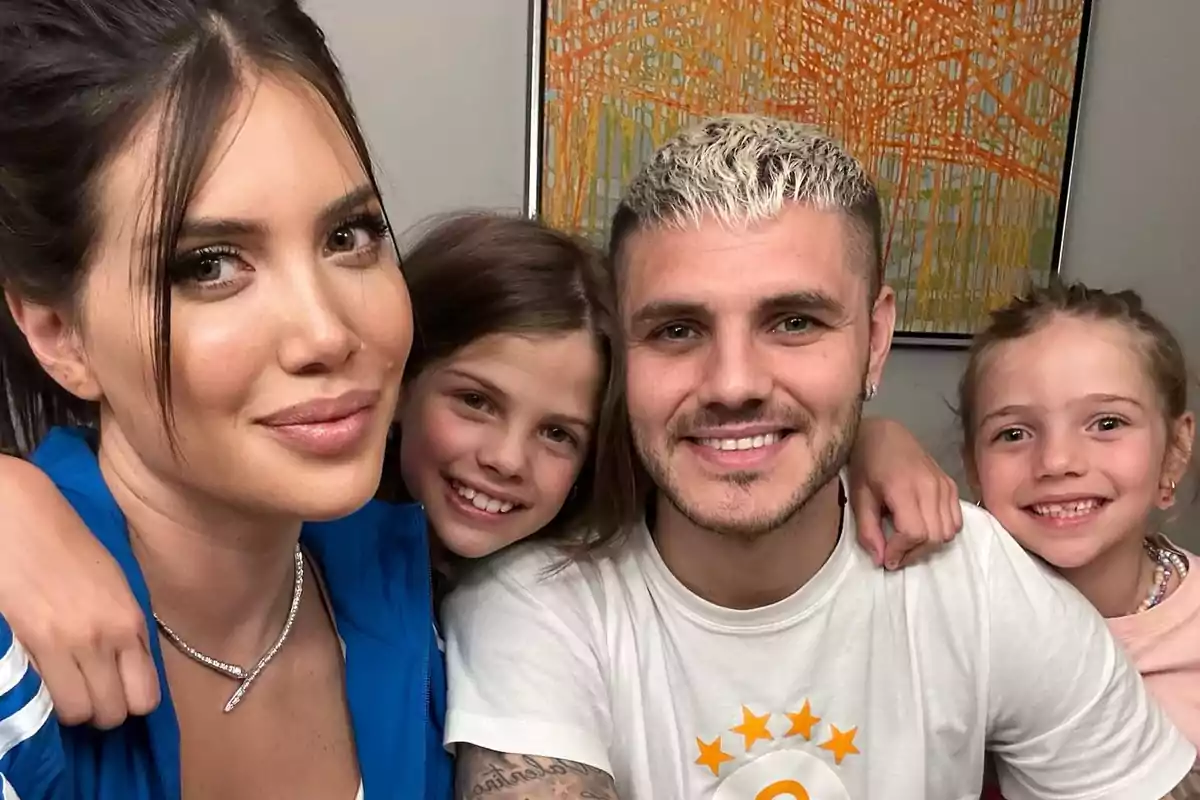 Una familia sonriente posando para una foto en un ambiente interior con un cuadro colorido de fondo.