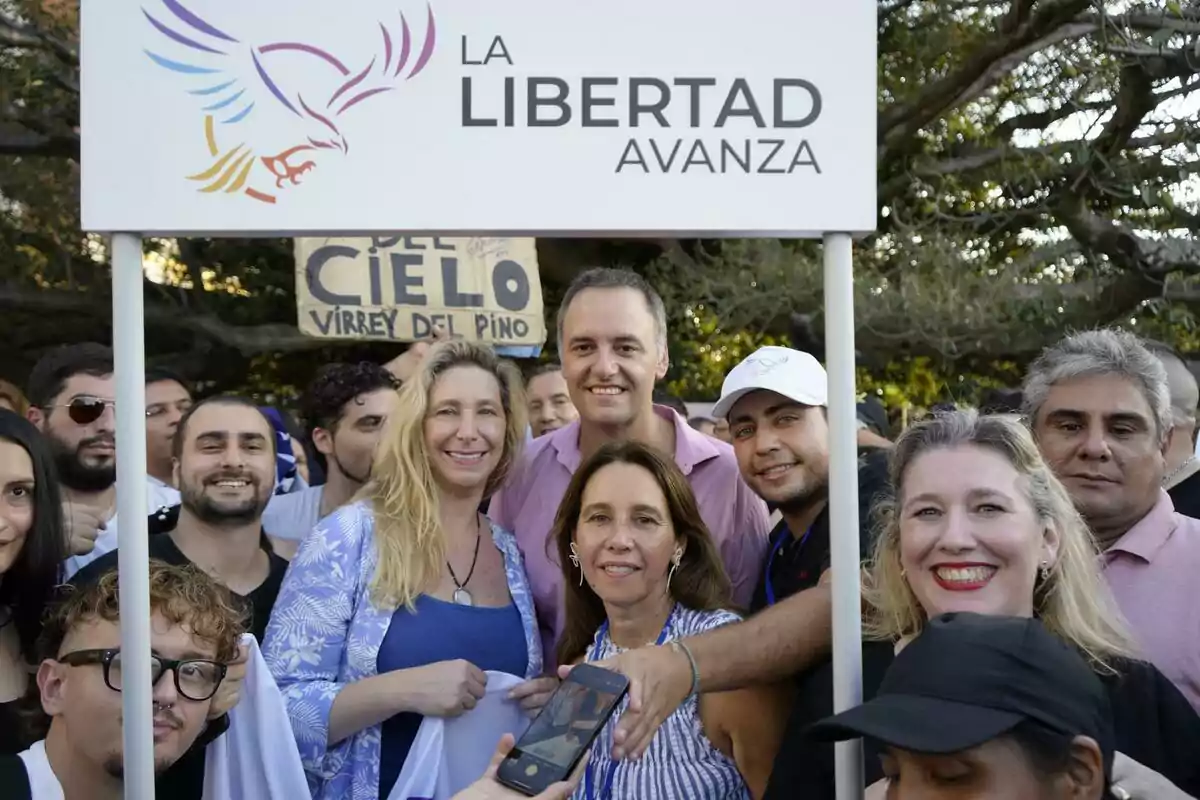 Un grupo de personas sonríe frente a un cartel que dice "La Libertad Avanza".