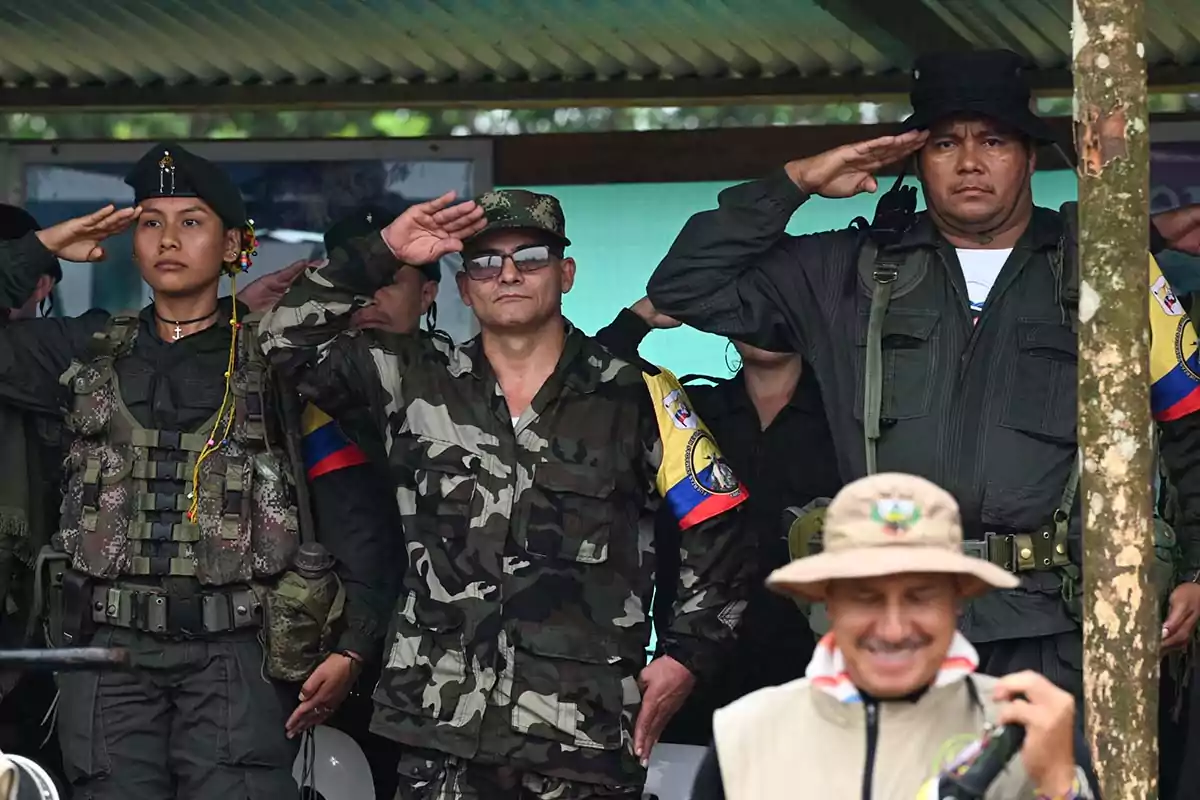 Un grupo de personas en uniforme militar realiza un saludo en una ceremonia al aire libre. Un grupo de personas en uniforme militar realiza un saludo en una ceremonia al aire libre.