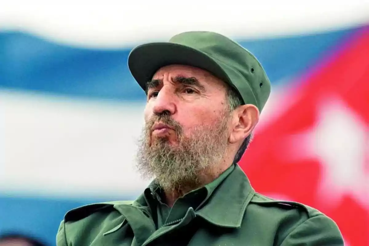 A man in a military uniform and green cap is standing in front of a blurred flag in the background. A man in a military uniform and green cap is standing in front of a blurred flag in the background.