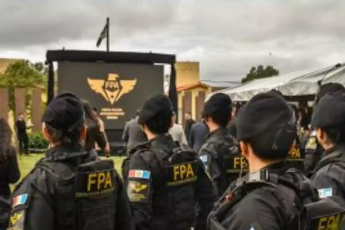 Grupo de agentes de la FPA en un evento al aire libre frente a una pantalla grande.