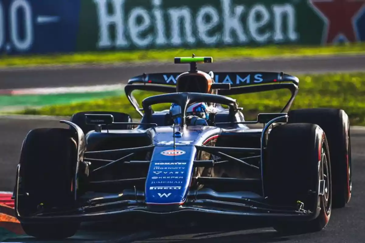 Un coche de Fórmula 1 del equipo Williams en la pista con un cartel de Heineken de fondo.