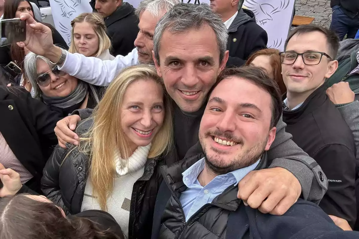 Un grupo de personas sonríe mientras se toma una selfie en un evento al aire libre.