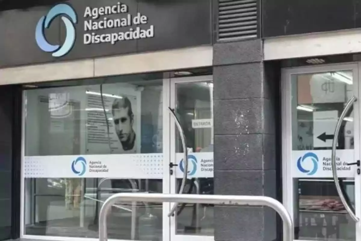 Fachada de la Agencia Nacional de Discapacidad con puertas de vidrio y un cartel con el logo de la institución.