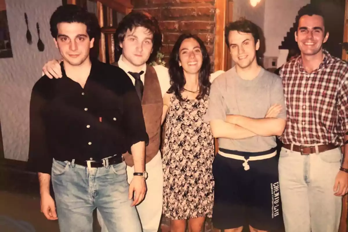 Un grupo de cinco personas posando juntas en un ambiente interior, con una pared de ladrillos y decoración hogareña al fondo. Un grupo de cinco personas posando juntas en un ambiente interior, con una pared de ladrillos y decoración hogareña al fondo.