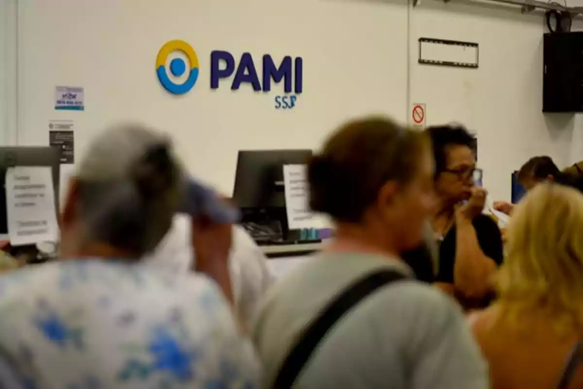 Personas esperando en una oficina con el logo de PAMI en la pared.