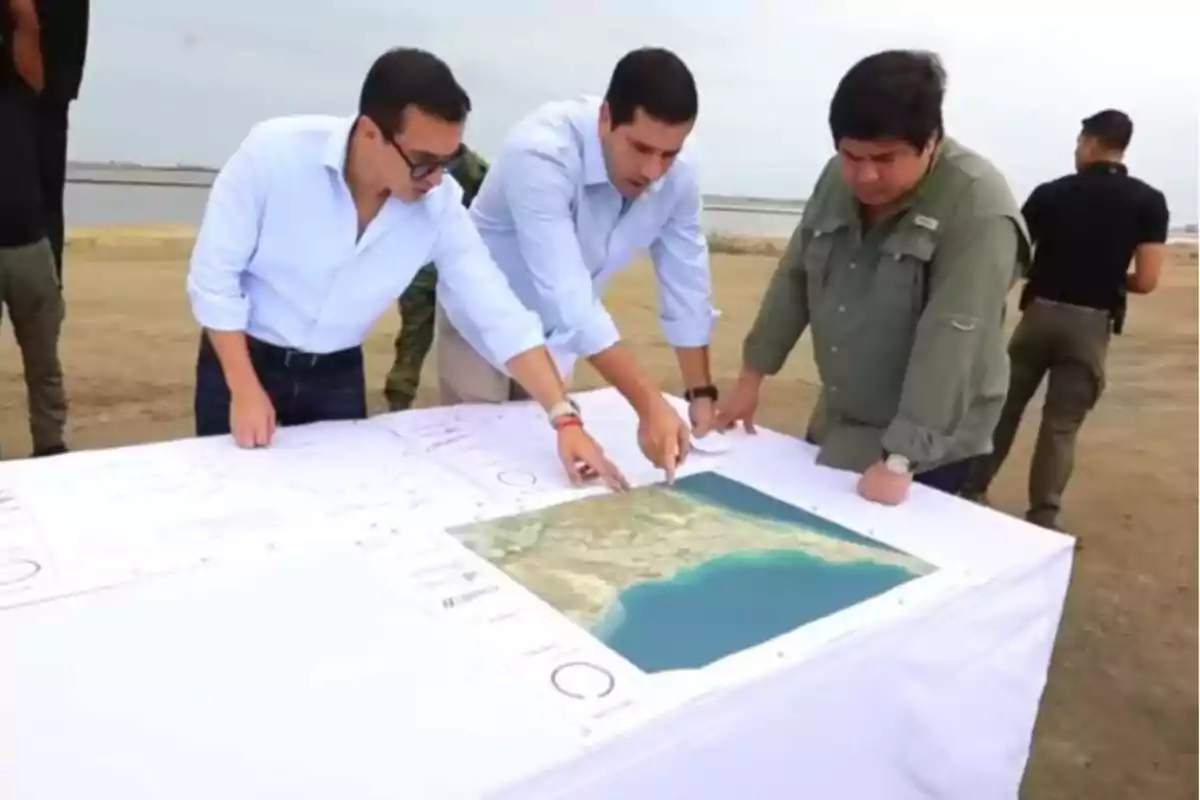 Un grupo de personas revisa un mapa sobre una mesa al aire libre en un entorno costero.