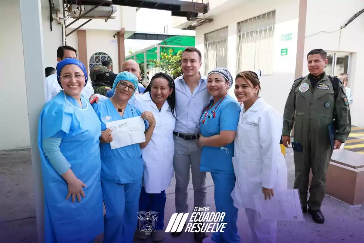 Un grupo de personas, algunas con uniformes médicos, posan sonriendo para una foto en un entorno exterior junto a un edificio.