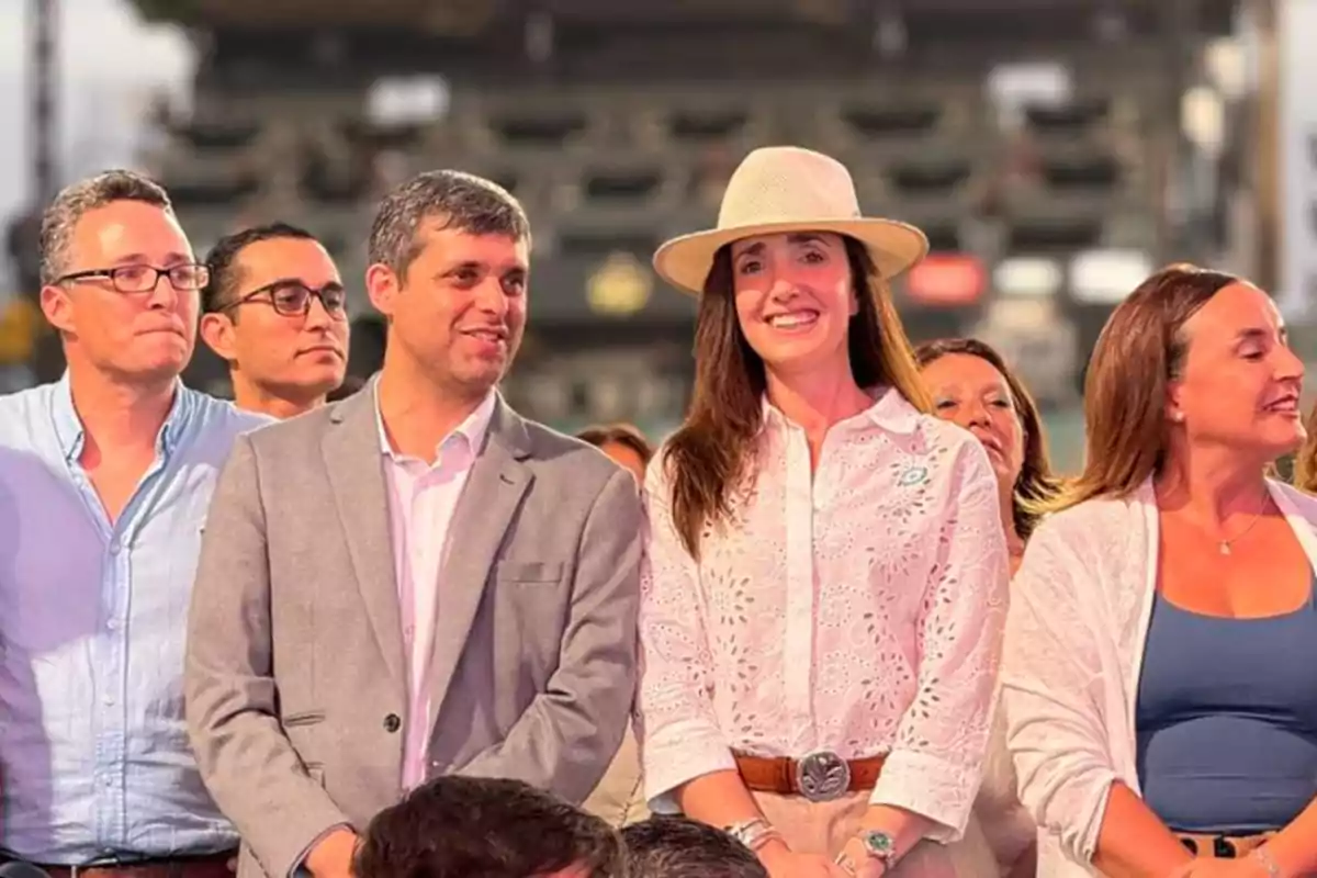 Un grupo de personas sonríe mientras asiste a un evento al aire libre.