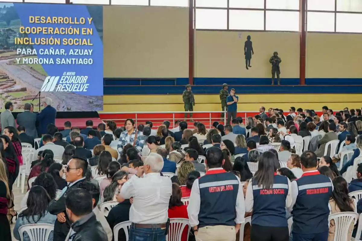 A conference on development and cooperation in social inclusion for Cañar, Azuay and Morona Santiago, with a large audience and security personnel present.