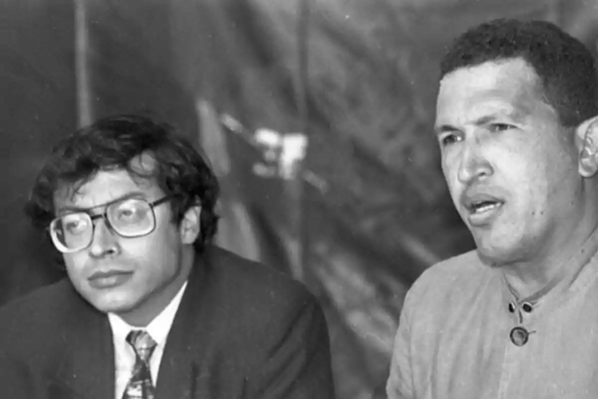 Dos hombres sentados en una conversación en blanco y negro.