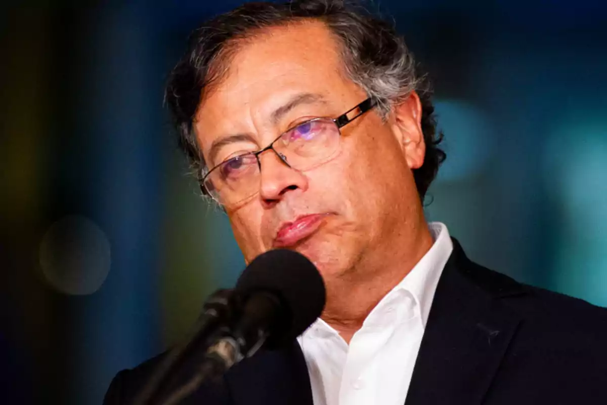 Un hombre con gafas y cabello canoso habla frente a un micrófono. Un hombre con gafas y cabello canoso habla frente a un micrófono.