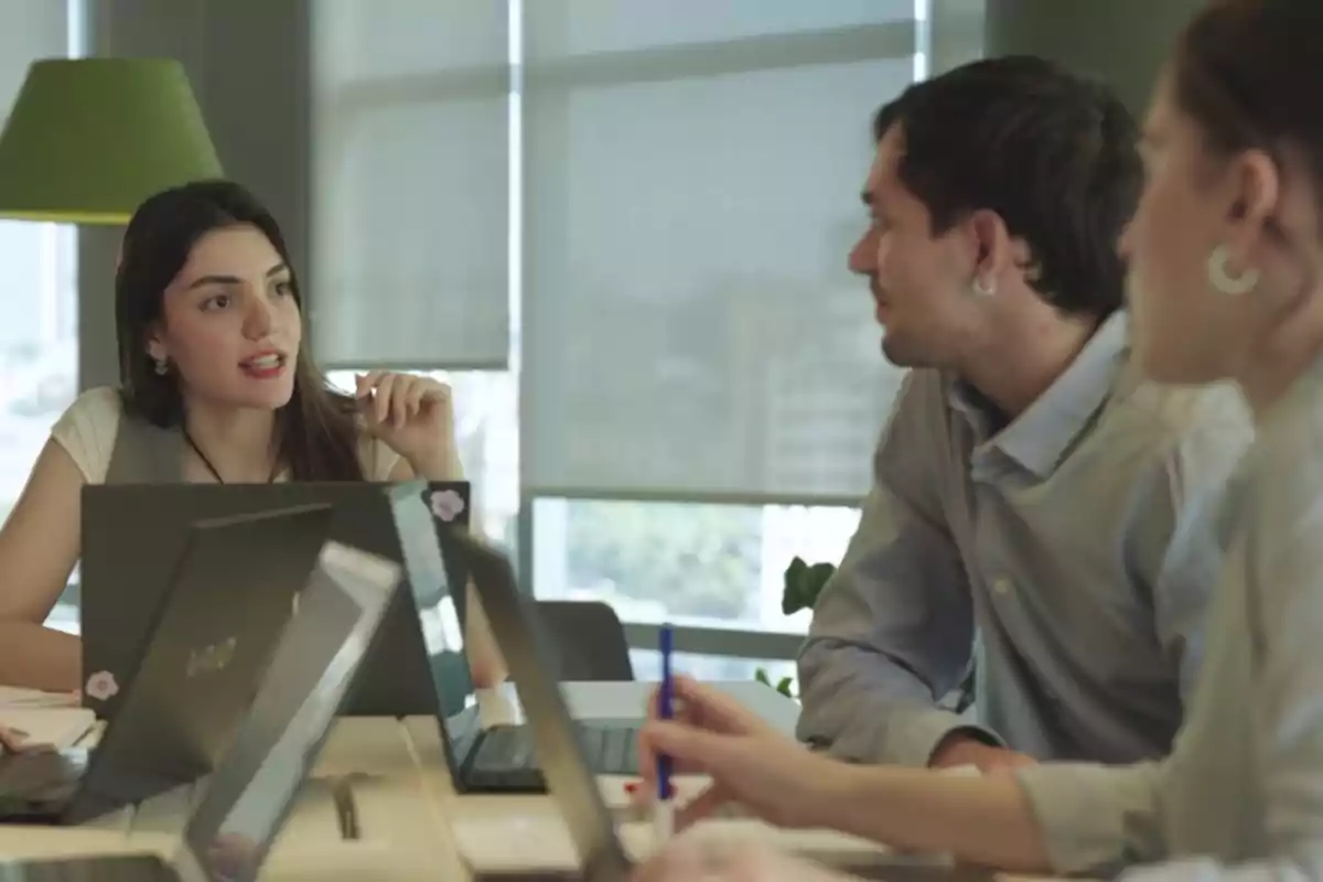 People in a work meeting with laptops on the table in a well-lit office. People in a work meeting with laptops on the table in a well-lit office.