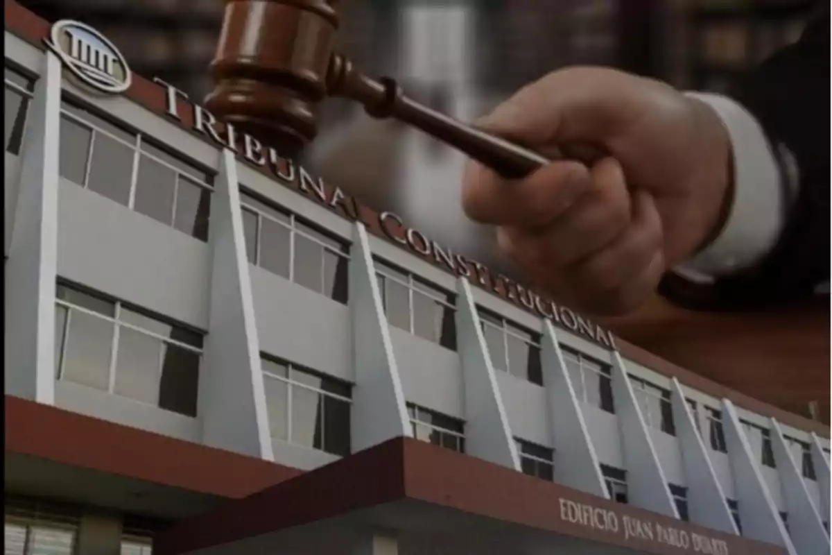 Fachada de un edificio del Tribunal Constitucional con una mano sosteniendo un mazo de juez en el fondo