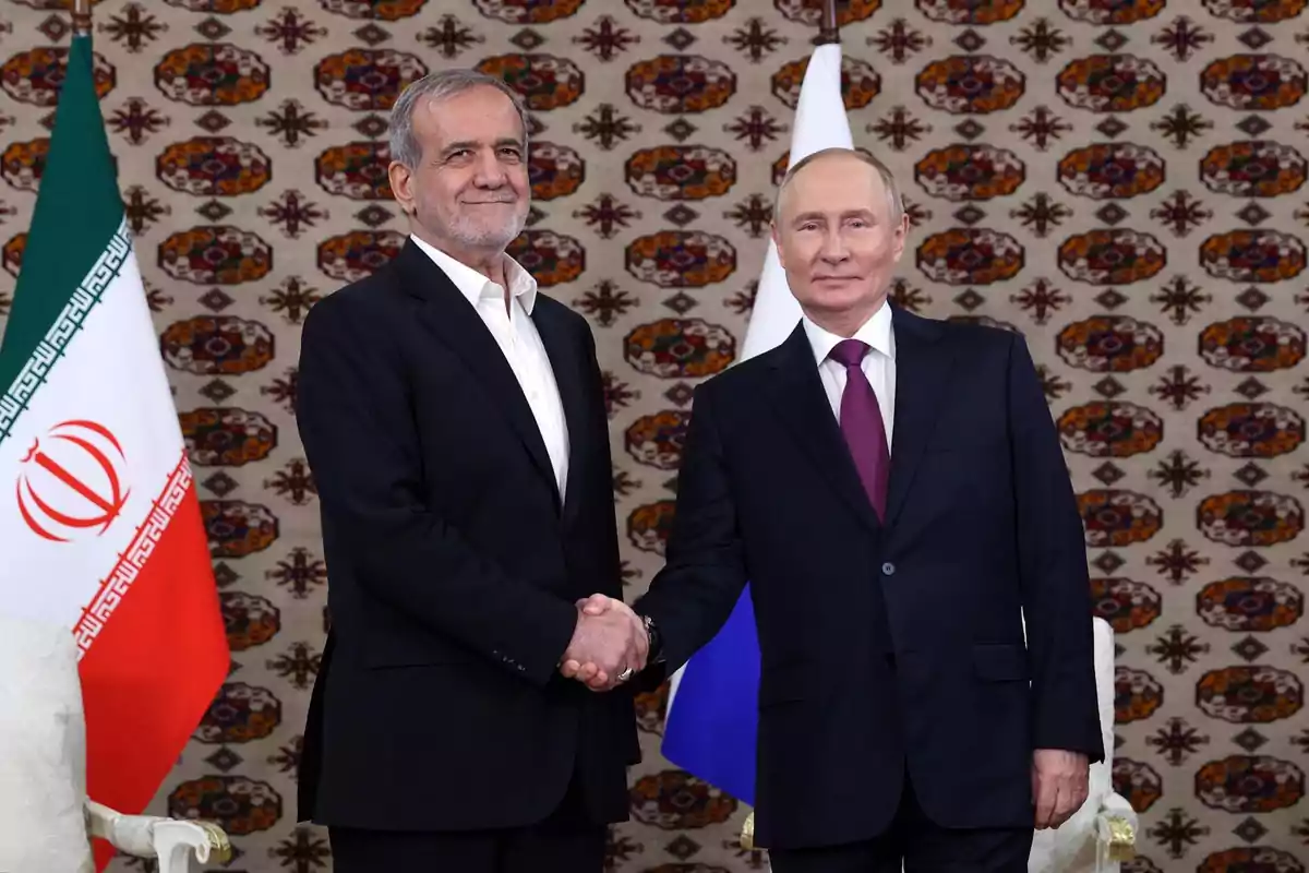 Two men in suits shake hands in front of the flags of Iran and Russia with a decorative background. Two men in suits shake hands in front of the flags of Iran and Russia with a decorative background.