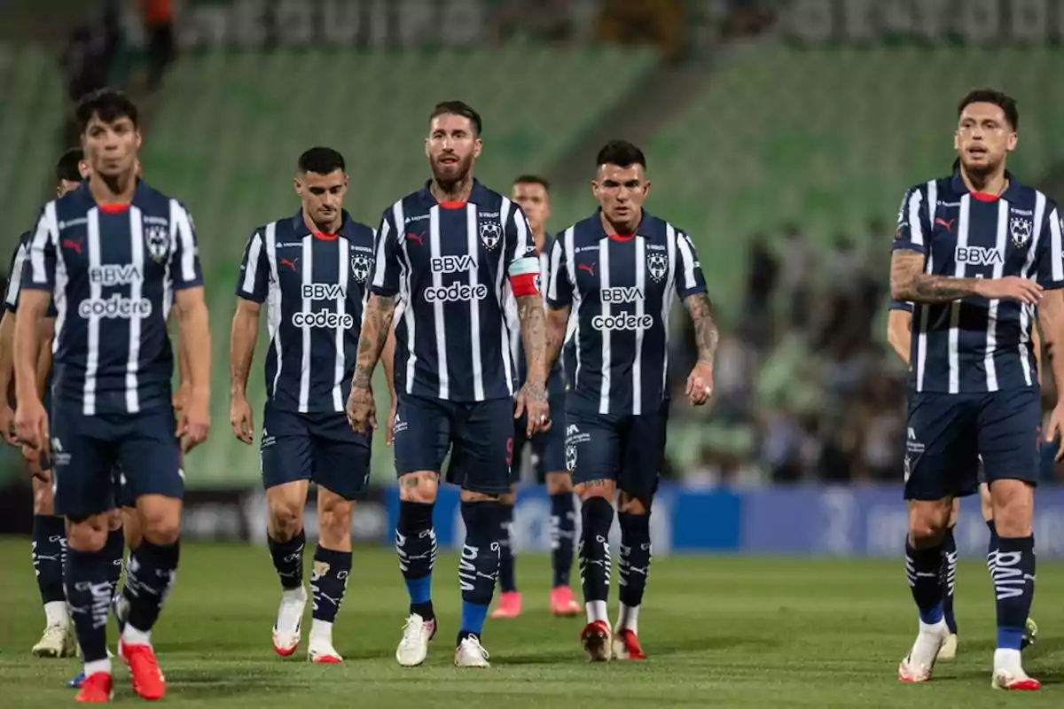 Jugadores de fútbol del equipo Monterrey caminando en el campo con uniformes a rayas azules y blancas. Jugadores de fútbol del equipo Monterrey caminando en el campo con uniformes a rayas azules y blancas.
