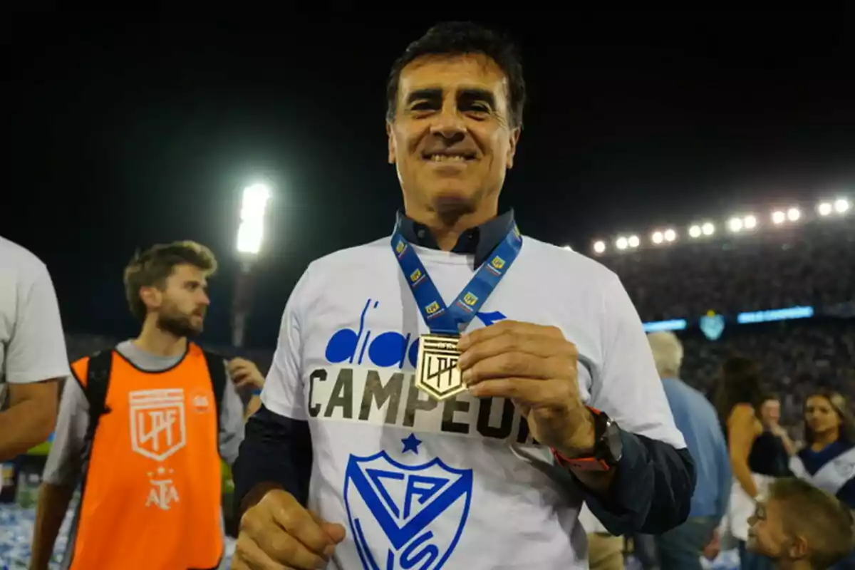 A smiling man holds a champion's medal in a crowded stadium. A smiling man holds a champion's medal in a crowded stadium.