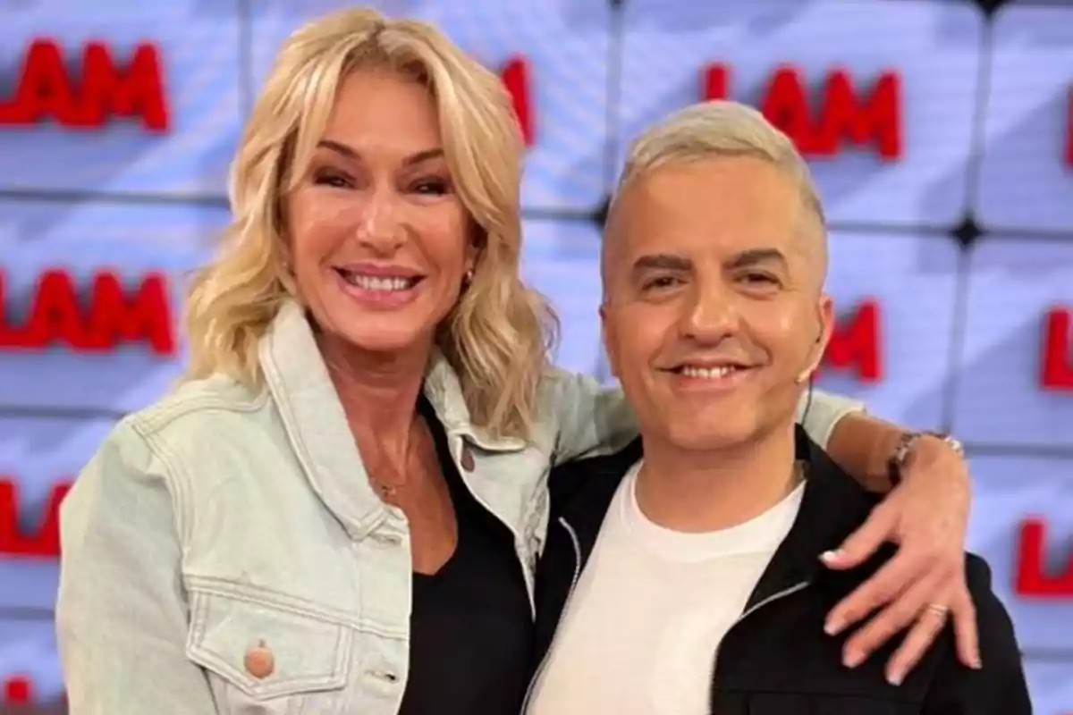 Dos personas sonrientes posan juntas frente a un fondo con el texto "LAM".