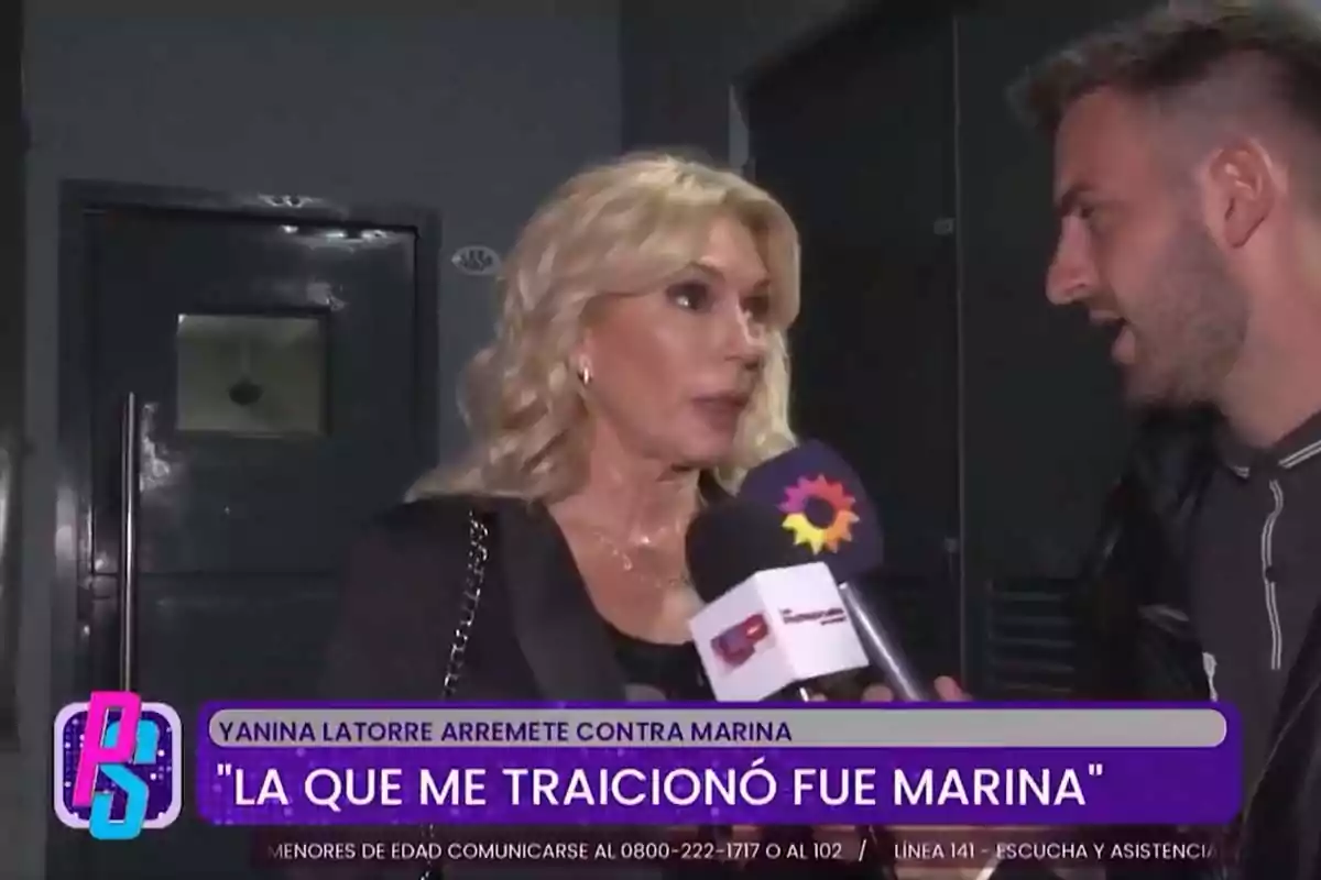 Una mujer rubia está siendo entrevistada por un reportero que sostiene un micrófono con un logotipo colorido, mientras un texto en la parte inferior de la imagen destaca una declaración sobre una traición. Una mujer rubia está siendo entrevistada por un reportero que sostiene un micrófono con un logotipo colorido, mientras un texto en la parte inferior de la imagen destaca una declaración sobre una traición.