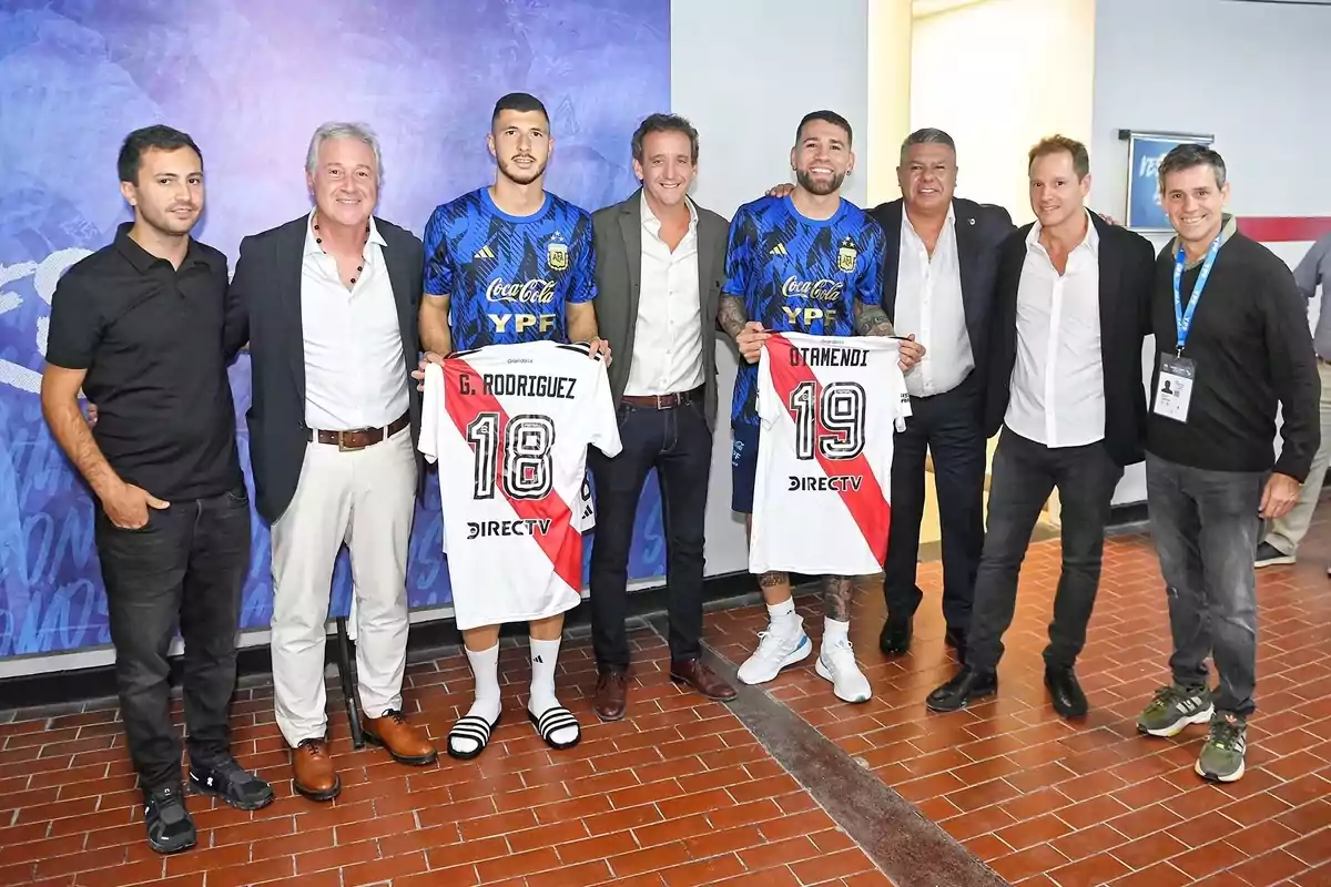 Grupo de hombres posando juntos mientras dos de ellos sostienen camisetas de fútbol de River Plate con los nombres G. Rodríguez y Otamendi Grupo de hombres posando juntos mientras dos de ellos sostienen camisetas de fútbol de River Plate con los nombres G. Rodríguez y Otamendi