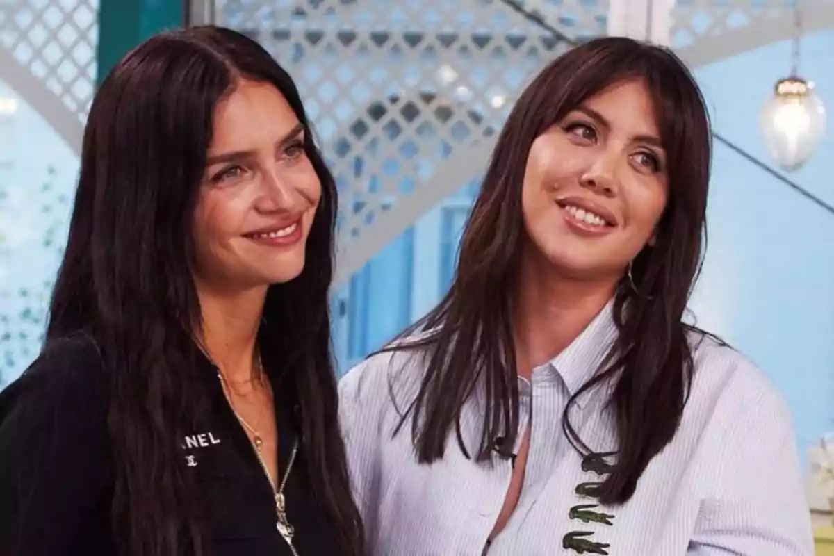 Dos mujeres de cabello largo y oscuro sonríen mientras posan juntas en un ambiente interior iluminado y decorado con tonos claros.