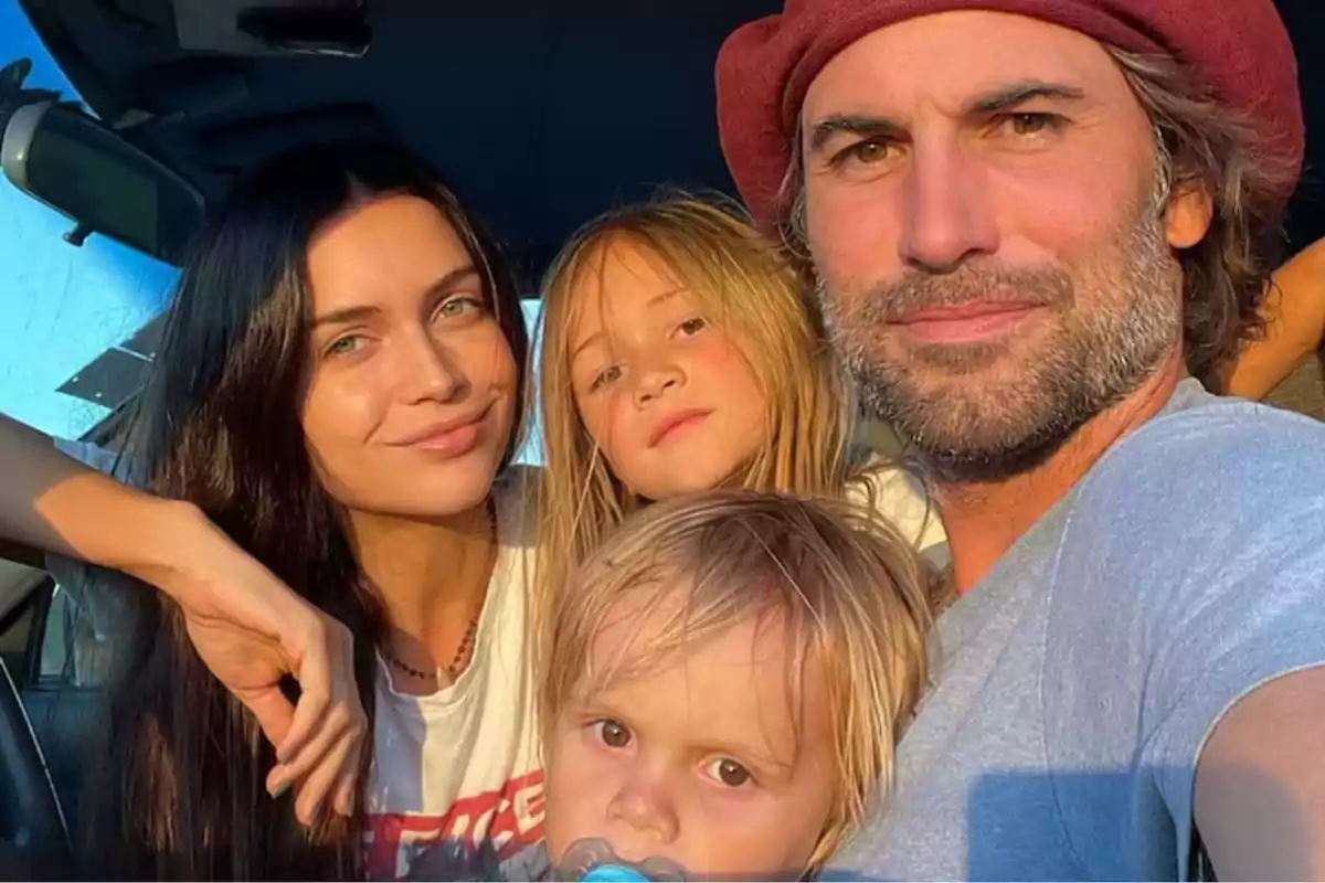 A smiling family posing for a photo inside a car with sunset light.