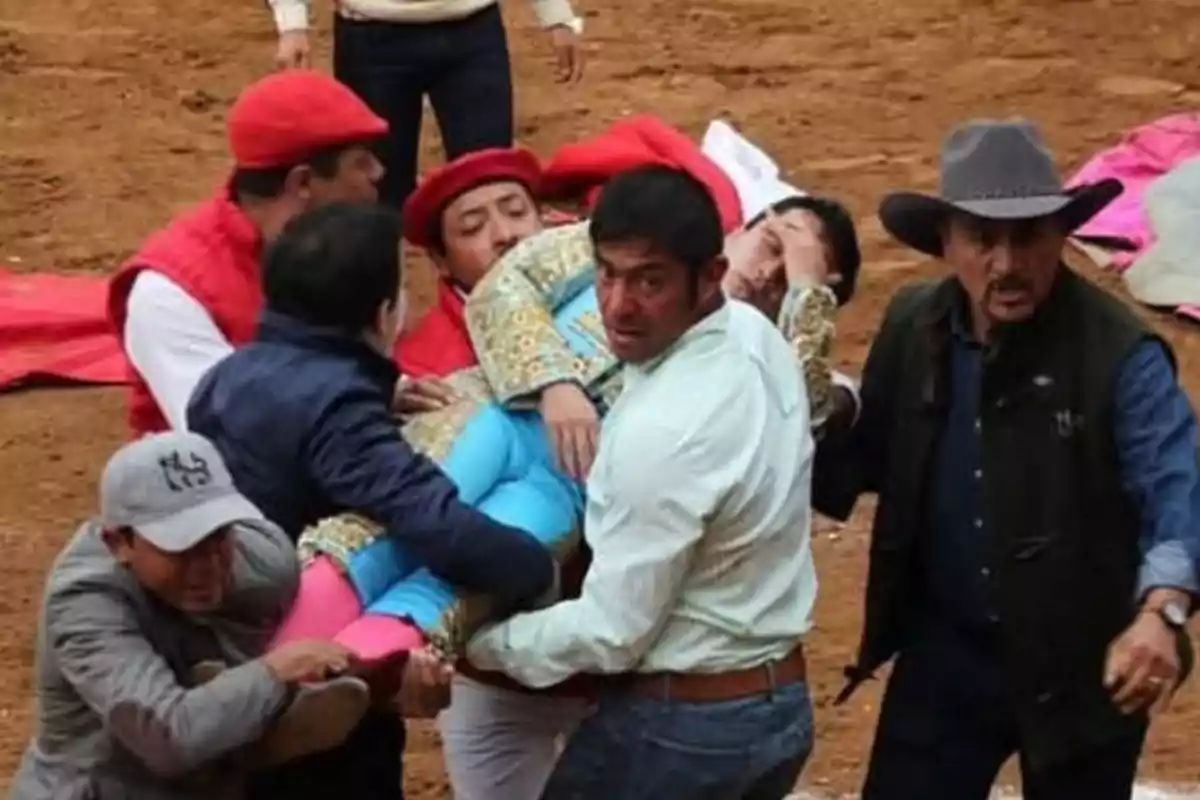 Un grupo de personas lleva a un torero herido fuera de la arena.